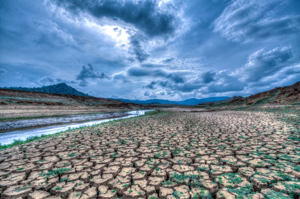 Cracked, parched earth in foreground, dramatic clouds in background