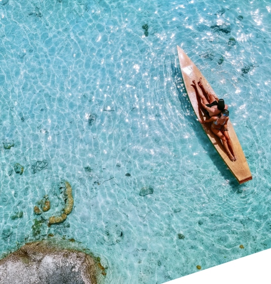 sc-cs-holidayextra-hero Two people sat on a wooden canoe in a lake